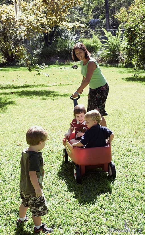 Mother pulling young children in wagon